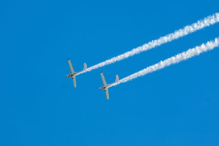 Stunt aerobatic plane performing stunts in blue sky with smoke trail. Concept of teamwork,...