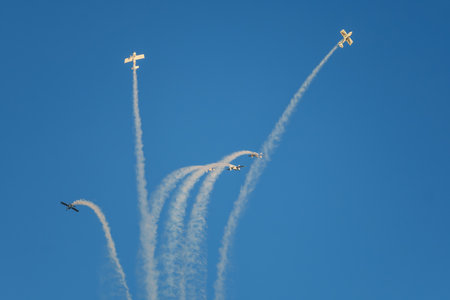 Stunt aerobatic planes performing stunts in blue sky with smoke trail. Concept of teamwork, collaboration, coordination, trust, precision, difficulty, challenge, speed, synergyの写真素材
