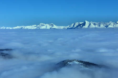 snowy mountain peak rises above the cloudsの写真素材