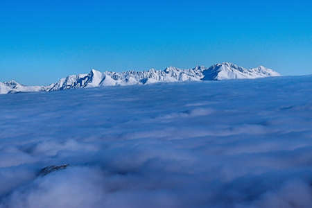 snowy mountain peak rises above the cloudsの写真素材
