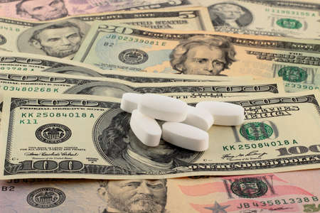Tablets on top of money. The rising cost of health care.の写真素材