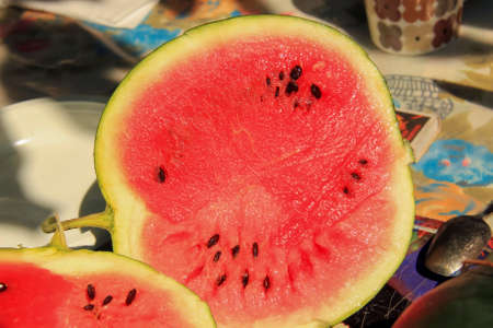 Ripe juicy watermelon cut into the table with black stonesの写真素材