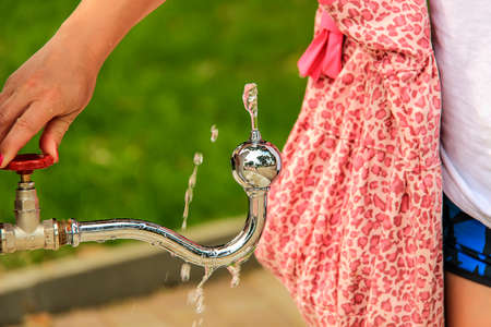 girl's hand is turn on faucet in the outdoorの写真素材