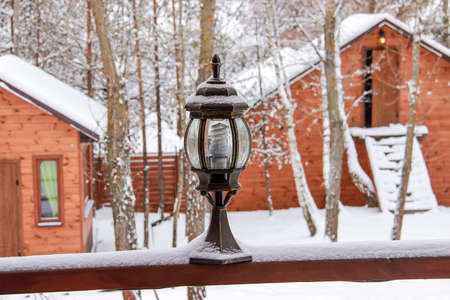 Lantern in the snow against the backdrop of snow-covered housesの写真素材