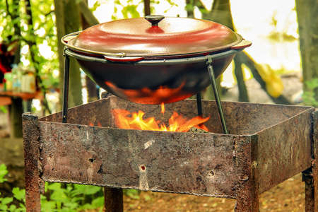 Tourist boiler with food standing on the grill over the fire. Focus on the pot.の写真素材