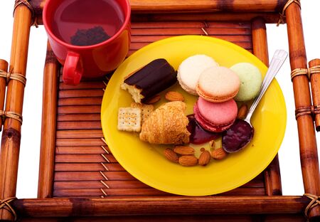 Breakfast with macaroons, croissant, eclair and almonds on the wooden trayの写真素材