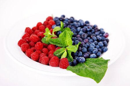Raspberry and blueberry with mint on white plateの写真素材