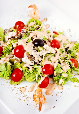 Salad with shrimp, tomatos and sauce on white plateの写真素材