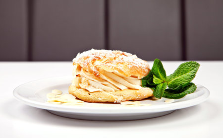 Pastry with sugar powder, almonds and mint on white background