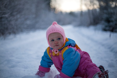 Portrait of baby girl crawling on the snow-covered footpath.の写真素材