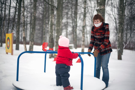 Mother is riding her little daughter on merry-go-round in winter day.