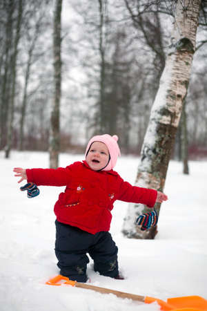 Little girl is standing with spread hands in the park in winter day.の写真素材