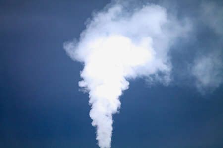 White smoke is coming out the chimney over the dramatic blue sky.の写真素材