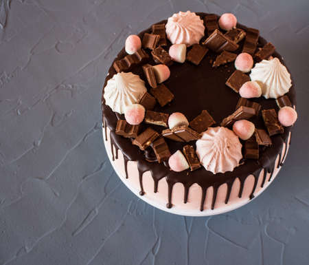 Biscuit cake with chocolate drips, marshmallows and marmalade, slice of chocolate. Sweets and foodの写真素材