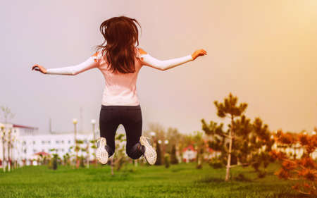 Young girl jumping and having fun for spring and sun on green grass. Leisure and lifestyleの写真素材