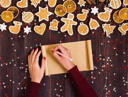 Woman hand holding pen empty paper for recipe christmas gingerbread baking. Top view of gingerbread man cookies cinnamon orangesの写真素材