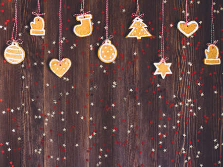 Gingerbread cookies on rope for christmas tree decoration new year on wooden table. Festive sweet pastry delicious food. Various cookies gingerbread star heart christmas ball sock Santa Claus mittenの写真素材