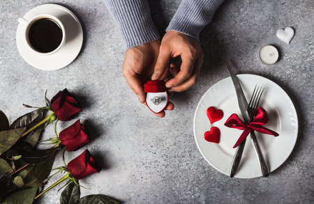 Valentines day romantic dinner table setting man hand holding engagement ring in box marry me...