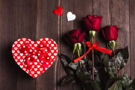 Valentines day womens mothers day red rose gift box heart shape surprise on dark wooden background. Love flower gift for woman on romantic holiday birthday weddingの写真素材