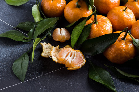 Tangerines with green leaves close up on dark background. Orange mandarins sweet fresh citrus fruit healthy food. Horizontal photoの写真素材