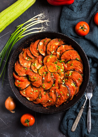 Ratatouille french provence dish of vegetables zucchini eggplant peppers and tomatoes in vintage frying pan on dark background. Healthy tasty foodの写真素材