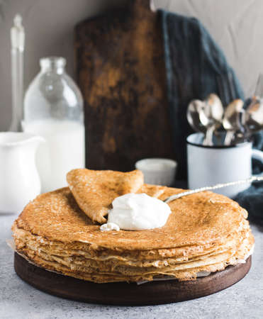 Pancakes crepes with sour cream russian traditional pancake week carnival pastry on light background. Rustic tasty baked pastry. Vertical photoの写真素材