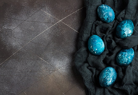 Easter eggs painted by hand in blue color on dark background. Chicken eggs catholic and orthodox...