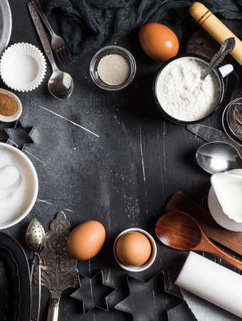 Preparation baking kitchen ingredients for cooking. Frame grocery accessories home pastry eggs flour sugar yeast milk spoon whisk for cooking food on dark background with copy space flat lay top viewの写真素材