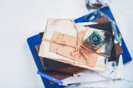 Header with writer workplace. Inkwell on a stack of drafts, pencil boxes and papers. High key still life. Creative writing concept with copy space.の写真素材