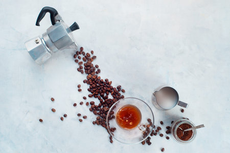 Pouring coffee beans from Moka pot in a glass espresso cup with a saucer. Creative top view hot drink concept with copy space. Brewing coffee in Moka pot concept.の写真素材
