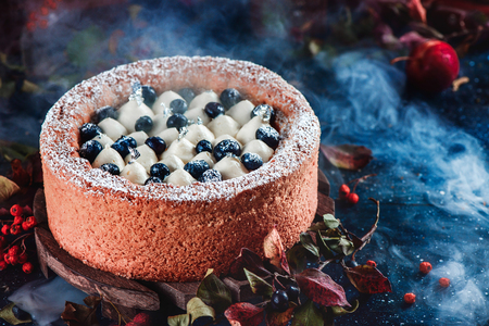 Whipped cream and blueberry cake with a shortbread crust on a dark background. Dark food photography with smoke. Traditional pumpkin pie in a Halloween still life with pastry.の写真素材