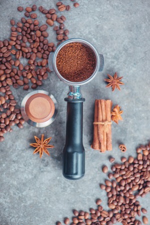 Portafilter with ground coffee, tamper, cinnamon and beans on a marble background. Coffee making equipment with copy space.の写真素材