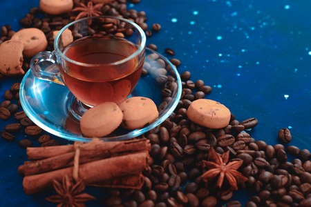 Close-up of a glass espresso cup with coffee beans, cinnamon, spices and cookies. Dark food photography with copy space.の写真素材
