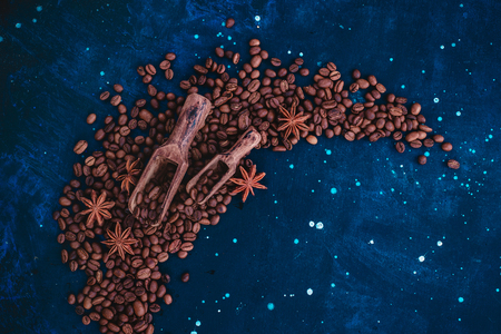 Wooden scoops for coffee beans in a vignette with copy space on a dark background. Ingredients for making coffee in a creative flat lay concept.の写真素材