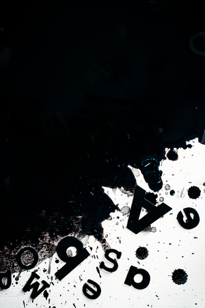 Scattered letters in blurring spilled ink. Creative writing concept. High contrast still life with creative writer workplace. Copy space.の写真素材