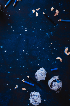 Dark background with crumpled paper balls, empty coffee cups, pencils, paper, notes and notepads. Still life with writer workplace. Creative writing concept.の写真素材