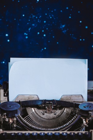 Modern typewriter with sheets of paper on a dark background. Editing and copywriting workplace. Creative writing concept.の写真素材