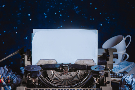 Modern typewriter with sheets of paper on a dark background. Editing and copywriting workplace. Creative writing concept.の写真素材