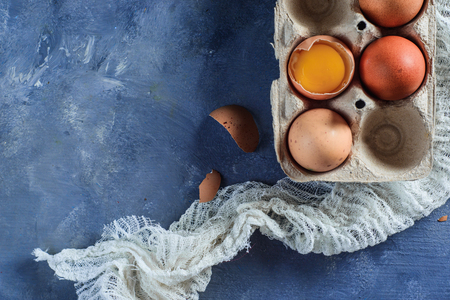 Broken egg with visible yolk in a carton. Close-up with copy space. Modern Easter concept with copy spaceの写真素材