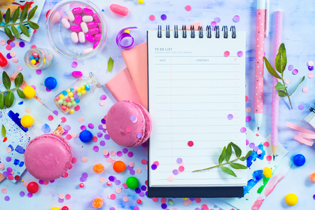 Party management and organization concept with sweets, confetti and an open notepad with blank pages. Creative celebration flat lay with copy space.の写真素材