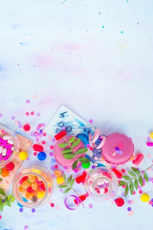 Colorful celebration flat lay with party supplies, confetti and sweets. Pink macarons overhead scene with copy space.の写真素材