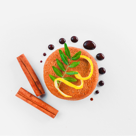 Cookie decorated with lemon zest, chocolate drops, cinnamon and green leaves on a white background. Pastry styling tips concept.の写真素材