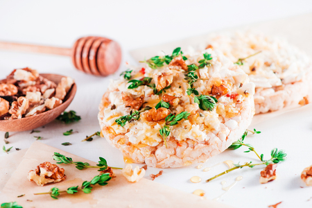 Healthy crisp bread toast with soft creamy cheese, honey, fresh thyme and nuts. Easy breakfast concept in high key with copy space.の写真素材