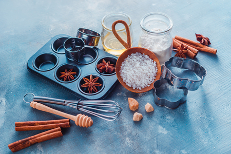 Muffin tin, sea salt, eggs, flour, oil and sugar with whisks and cookie cutters on a modern concrete background with copy space. Making pastry concept.の写真素材