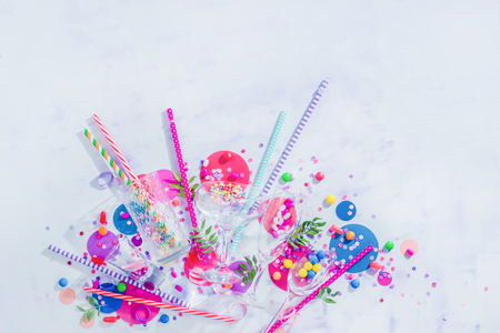 Cocktail glasses variety from above with straws, candies and confetti. Party concept with bar supplies, colorful flat lay with copy spaceの写真素材