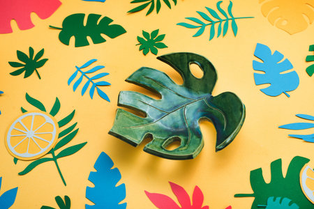 Ceramic monstera leaf in tropical header with oranges, leaves and fruits pattern on a bright yellow...