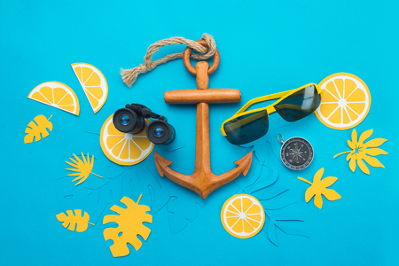Sea travel background with sunglasses, binoculars, anchor, compass and tropical leaves on a bright blue background. Summer vacation concept with copy spaceの写真素材