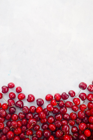 Sweet fresh cherries scattered on white marble backdrop. Healthy food background top view with copy space.の写真素材