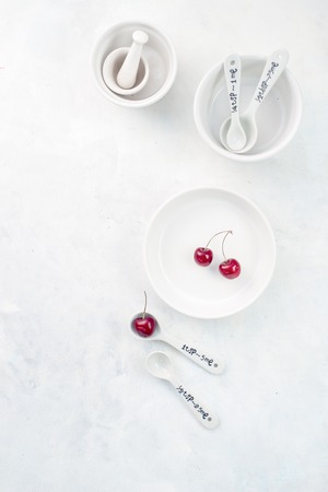 Minimalist empty porcelain dishes on a white stone background with copy space. Cherry pie baking concept.の写真素材