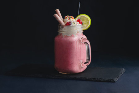 Cold strawberry milkshake in a vintage glass mason jar. Dark background with copy space for a menu.の写真素材